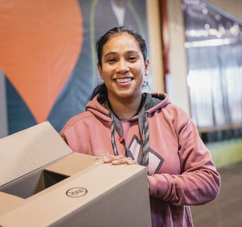 A smiling volunteer holding a box.