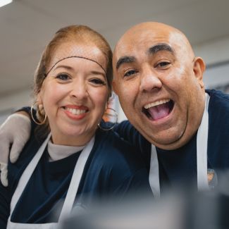 Volunteers smiling while wearing aprons, hairnets and gloves.