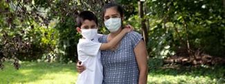 Mother and son hugging outside while wearing masks