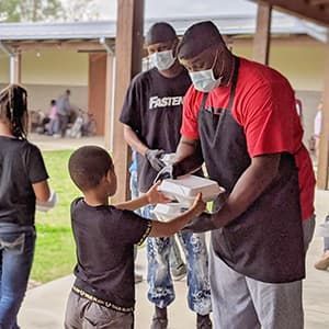Chef Grant passing out food to a child.