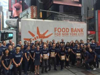 Volunteers standing in front of a Food Bank for New York City sign for a photo.