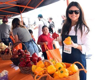 Tiffani Thiessen passes out bell peppers to children to take home for their families. 