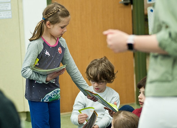 Hungry To Help Lesson Plan 2 A second grader hands out materials from the Hungry to Help lesson to her classmates.