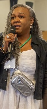 A woman standing and speaking into a microphone.