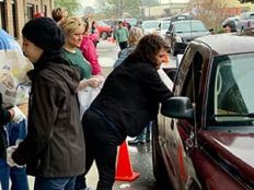 Volunteers and staff distribute food at a drive-up distribution.