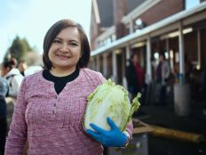 A woman in a pink sweater holding a head of lettuce