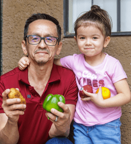 A father and daughter holding fresh vegetables 