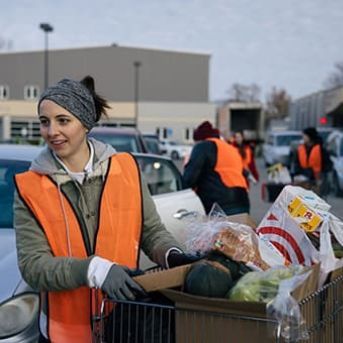 Young woman in an orange vest with shopping cart