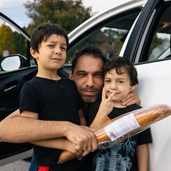 Anwar and his sons pose in front of his car during a distribution at an elementary school