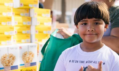 A little boy smiling at a food distribution location.