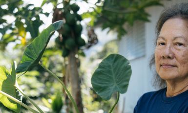 Older woman standing in front of a tree.