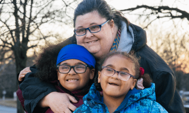 Heather hugging her children outside.