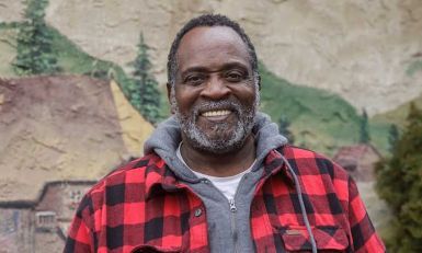 Frederick standing outside of a food bank while smiling.
