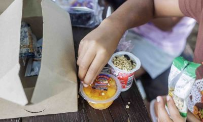 A child eating a meal on a park bench.