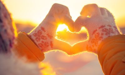 Hands forming a heart with a sunset in the background.