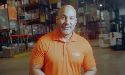 Paco Velez, CEO of Feeding South Florida, stands in the organization’s warehouse wearing an orange Feeding South Florida polo.