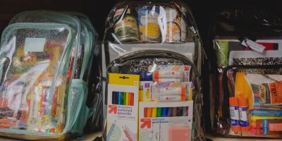 Photo of backpacks filled with canned food and school supplies