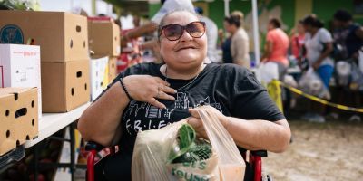 Photo of a woman with a bag of food at a food distribution location