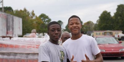 Two young volunteers helping at an outdoor food distribution.
