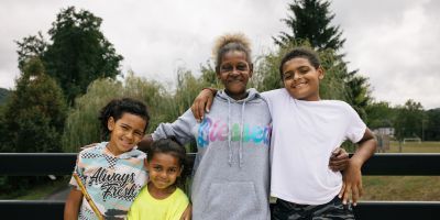 A grandmother and three grandsons, standing and smiling.