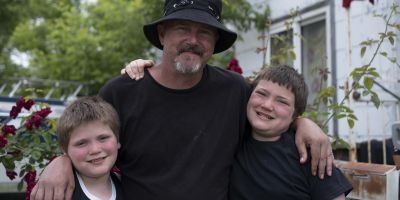 A father and two sons standing outside.