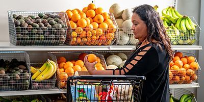 Adriana in front of shelves of fruits and vegetables.