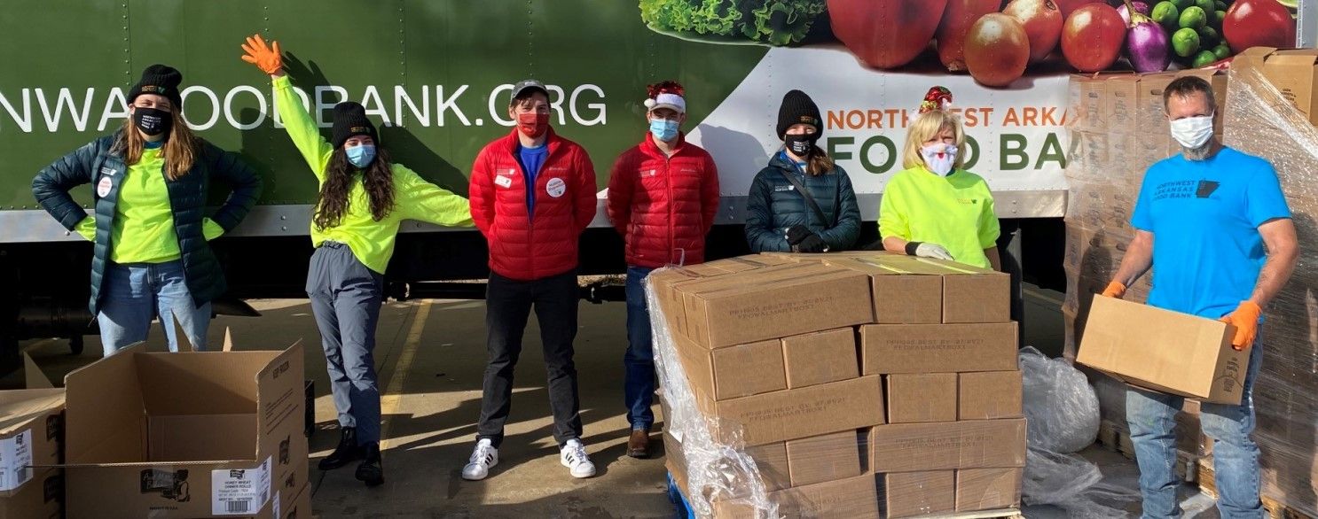 a group of volunteers in masks pose in front of a mobile pantry truck