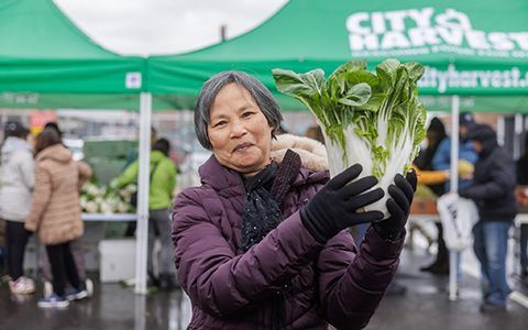 Mu Xiang holding a cabbage at a outdoor pantry.
