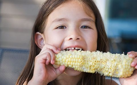 Girl eating corn.