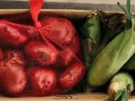 A box of fresh food - potatoes, corn