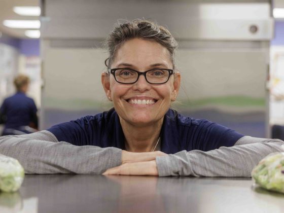 Nancy standing in a school cafeteria kitchen.