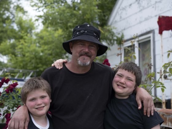 A father and two sons standing outside.