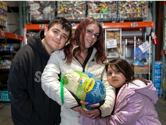 Mother and two children holding a turkey at a food distribution.