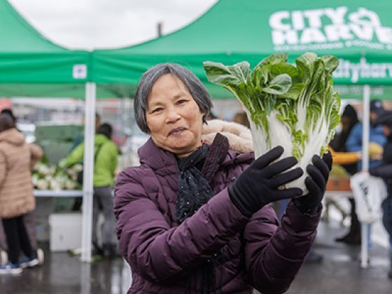 Mu Xiang holding a cabbage at a outdoor pantry.