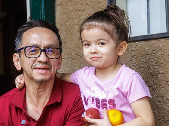 Pedro and his daughter holding fruit and smiling.