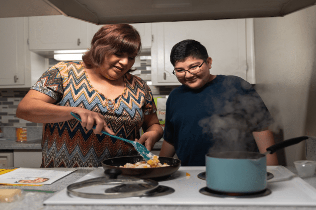 Elodia and Junior cooking a meal on the stove.