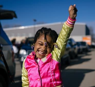 Young girl in pink vest raising hand in air