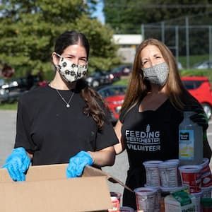 Mother and daughter volunteering at a mobile pantry.