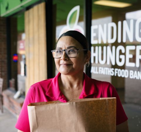 A food bank worker holding a bag of food.