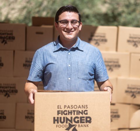 A person holding a box of food and smiling.