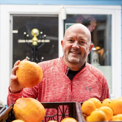 A volunteer smiling and holding a navel orange.