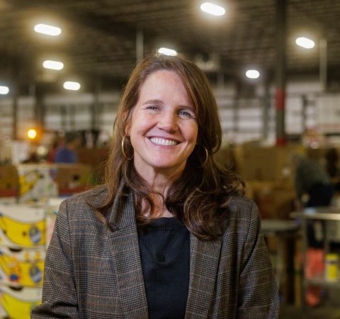 Claire standing in a food bank warehouse.