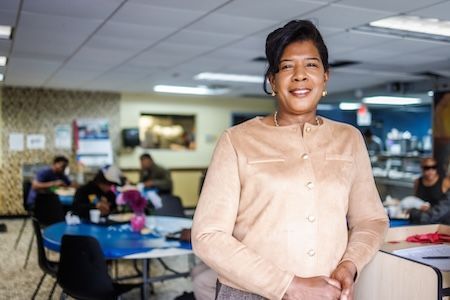 A food pantry leader smiling in front of people at tables