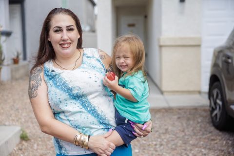 Mother holding her child who has an apple, representing a family that receives food access from the Feeding America and Tyson Foods partnership