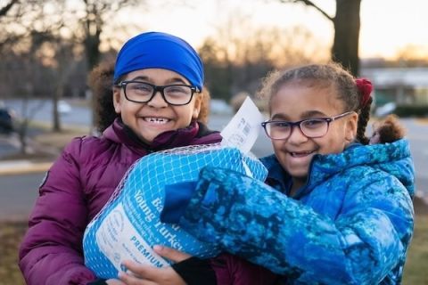 Two children grinning and holding a turkey