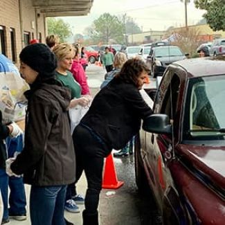 Volunteers and staff distribute food at a drive-up distribution.
