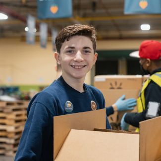 A volunteer with a food box at a packing facility.