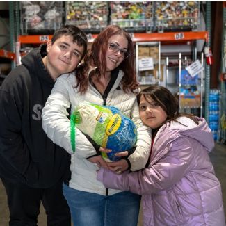 Mother and two children holding a turkey at a food distribution.