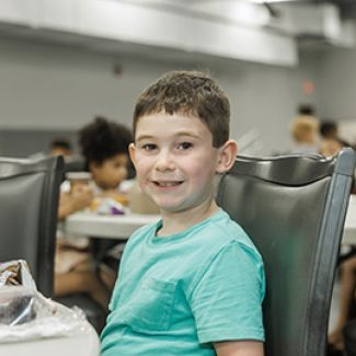 Tristan sitting at a table and eating lunch.