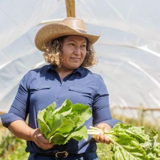 Maxi Hernandez holding produce on her farm.